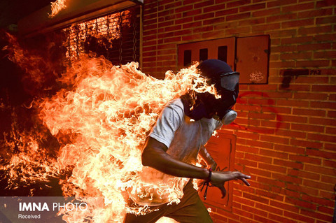"رونالدو اشمیت"
(Ronaldo Schemidt)
 عکاس ونزوئلایی آژانس عکس فرانس پرس ساکن مکزیک با ⁣عکسی از اعتراضات مردمی در ونزوئلا ⁣جایزه عکس سال ۲۰۱۸ ورلدپرس فوتو را از آن خود کرد.