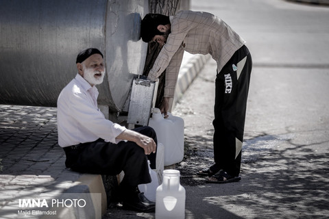 پیرمردی که برای پر کردن دبه ی آب خود از جوانی کمک میگیرد