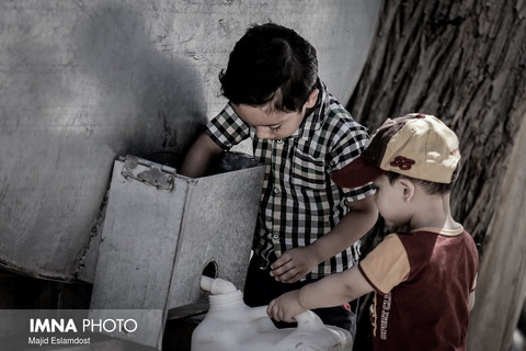 کودکی که به دوست خود برای پرکردن دبه ی آب کمک میکند