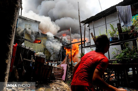 پاشیدن آب به سمت خانه آتش گرفته در فیلیپین 