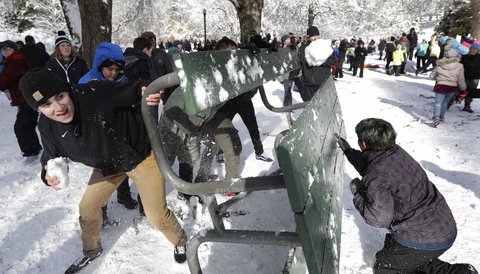 People taking part in a public snowball fight use a table as shield at Wright Park
