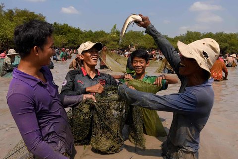 A man holds up a snake fish during a ceremony at Choam Krovean commune

