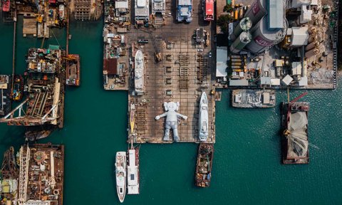 A 121-foot-long inflatable installation of American contemporary artist Brian Donnelly’s famous Companion seen at rest in a shipyard . The figure is part of a project, titled KAWS:HOLIDAY, and is part of Art Basel, Hong Kong.