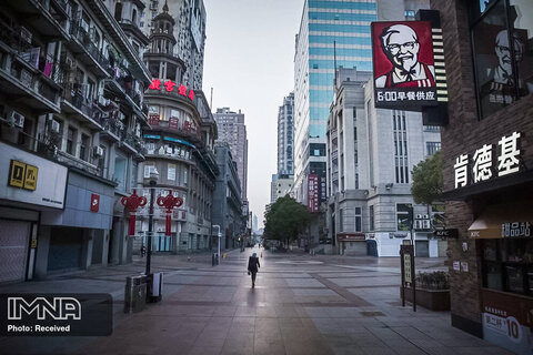 یکی از ساکنین در حال قدم زدن در خیابان خالی در شهر ووهان چین