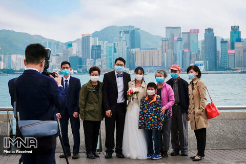 زن و شوهر تازه عروس هنگام عکسبرداری از مراسم عروسی با خانواده به همراه ماسک های محافظ