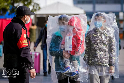 مسافران پوشیده از ماسک و پوشیده از کیسه های پلاستیکی در ایستگاه راه آهن شانگهای چین