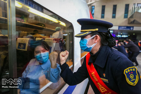  یک سرنشین قطار در حال خروج از شهر ووهان چین با پرسنل پزشکی خداحافظی می کند