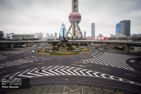 یک افسر پلیس در حال پیاده روی در یک جاده خالی جلوی برج مخابراتی در منطقه مالی شانگهای چین