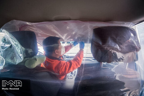 یک راننده در حال روکش پلاستیکی کردن خودرو برای جدا کردن صندلی های جلو از عقب برای سرویس دهی 