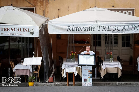 یک کارگر در رم ایتالیا در کنار یک رستوران خالی ایستاده است