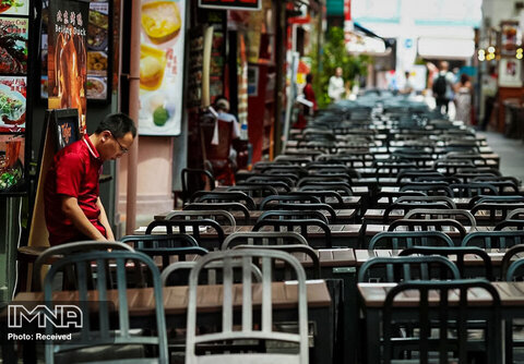یک کارگر رستوران در سنگاپور در انتظار مشتریان است