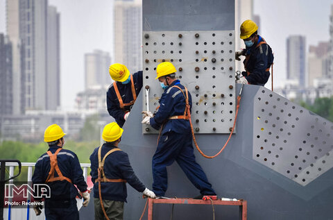 پس از از سرگیری کار ساخت و ساز کارگران روی یک پل در شهر ووهان کار می کنند