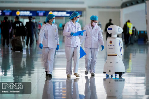 پس از برداشته شدن محدودیت های سفر کارمندان پزشکی با یک ربات پلیس در فرودگاه بین المللی ووهان تیانه قدم می زنند