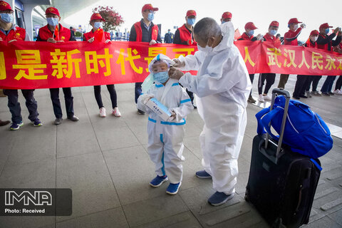 مسافران از ماسک و لباس های صورت برای محافظت در برابر شیوع کرونا ویروس استفاده می کنند و با بدرقه شهروندان شهر ووهان به شهر های خود بازمی گردند