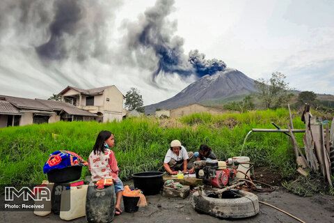 روستائیان سوماترا ، اندونزی در حال شستن لباس های خود در کنار کوه  Sinabung در هنگام فوران مواد آتشفشانی