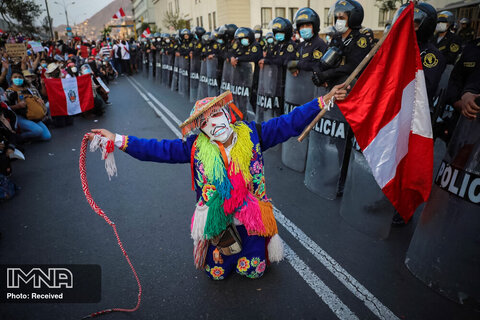هنرمندان محلی محلی در كنار یك خط پلیس در خارج از ساختمان كنگره اجرا می كنند ، زیرا آنها منتظر اخباری درباره رئیس جمهور بعدی این كشور در لیما ، پرو هستند
