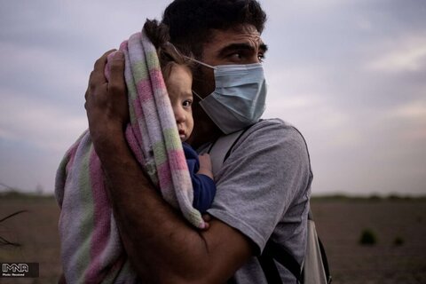 یک پناهنده از هندوراس ، دختر خود را در سرمای صبح در گهواره قرار می دهد. پناهندگان هندوراسی پس از عبور سخت و دشوار از رودخانه ریو گرانده در مرز مکزیک و آمریکار در انتظار انتقال به مرکز گشت مرزی ایالات متحده آمریکا هستند.
