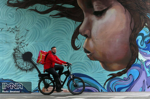 دوچرخه سواری مردی در مقابل نقاشی دیواری زیر پل قدیمی ساوا بر روی رودخانه ساوا در بلگراد  صربستان 