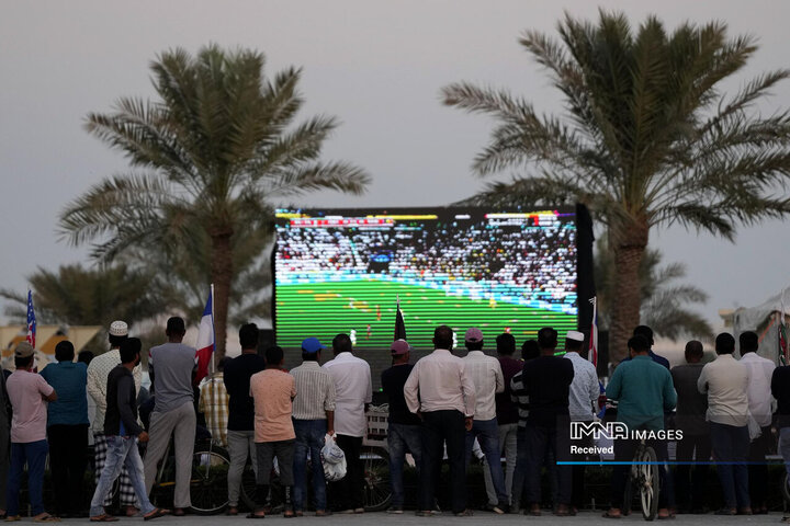 مردم مسابقه فوتبال بین قطر و سنگال را در یک منطقه تماشای عمومی تماشا می کنند