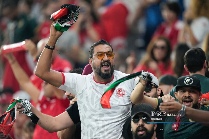 یکی از هواداران پرچم فلسطین را در حالی که در طول مسابقه تشویق می کند در دست دارد