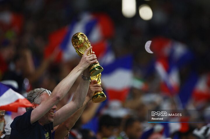 یک هوادار فرانسه یک کپی جام جهانی را قبل از مسابقه در استادیوم نگه می دارد