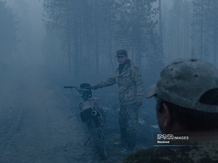 داوطلبان آتش نشان محلی اندازه آتش سوزی جنگل را در کورلیاخ، ساخا، روسیه بررسی می کنند. اندازه آتش فقط در شب، زمانی که رطوبت کمی آن را آرام می کند، قابل تشخیص است.