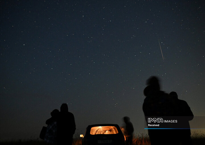 مردم در طول بارش سالانه شهاب‌سنگ در شهر ینی‌سیسک سیبری در منطقه کراسنویارسک، روسیه، رگه‌های شهابی را در آسمان شب تماشا می‌کنند.
