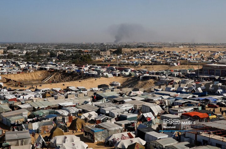 اردوگاه پناهجویان فلسطینی در رفح در حالی که دود ناشی از حملات زمینی اسرائیل در دوردست مشاهده می شود. 