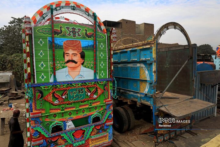 پرتره ای از جلال چندیو خواننده محلی سندی در پشت یک کامیون تزیین شده در پارکینگ یک کارگاه در پیشاور، پاکستان