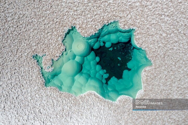 یک دریاچه کوچک و کم‌عمق مانند چشمی فیروزه‌ای در یکی از دشت‌های نمکی مرتفع واقع در شمال شیلی به نظر می‌رسد. آب زلال و کریستالی، خوشه‌هایی از سازندهای گرد و سفید مانند حباب‌های نمک را آشکار می‌کند. این ساختارهای طبیعی، ترکیبی منحصر به فرد و سورئال از رنگ و بافت به برکه می‌دهند.